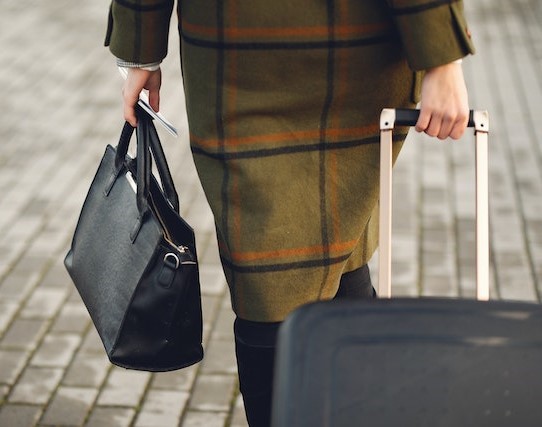 Woman walking away with suitcase, handbag and tickets