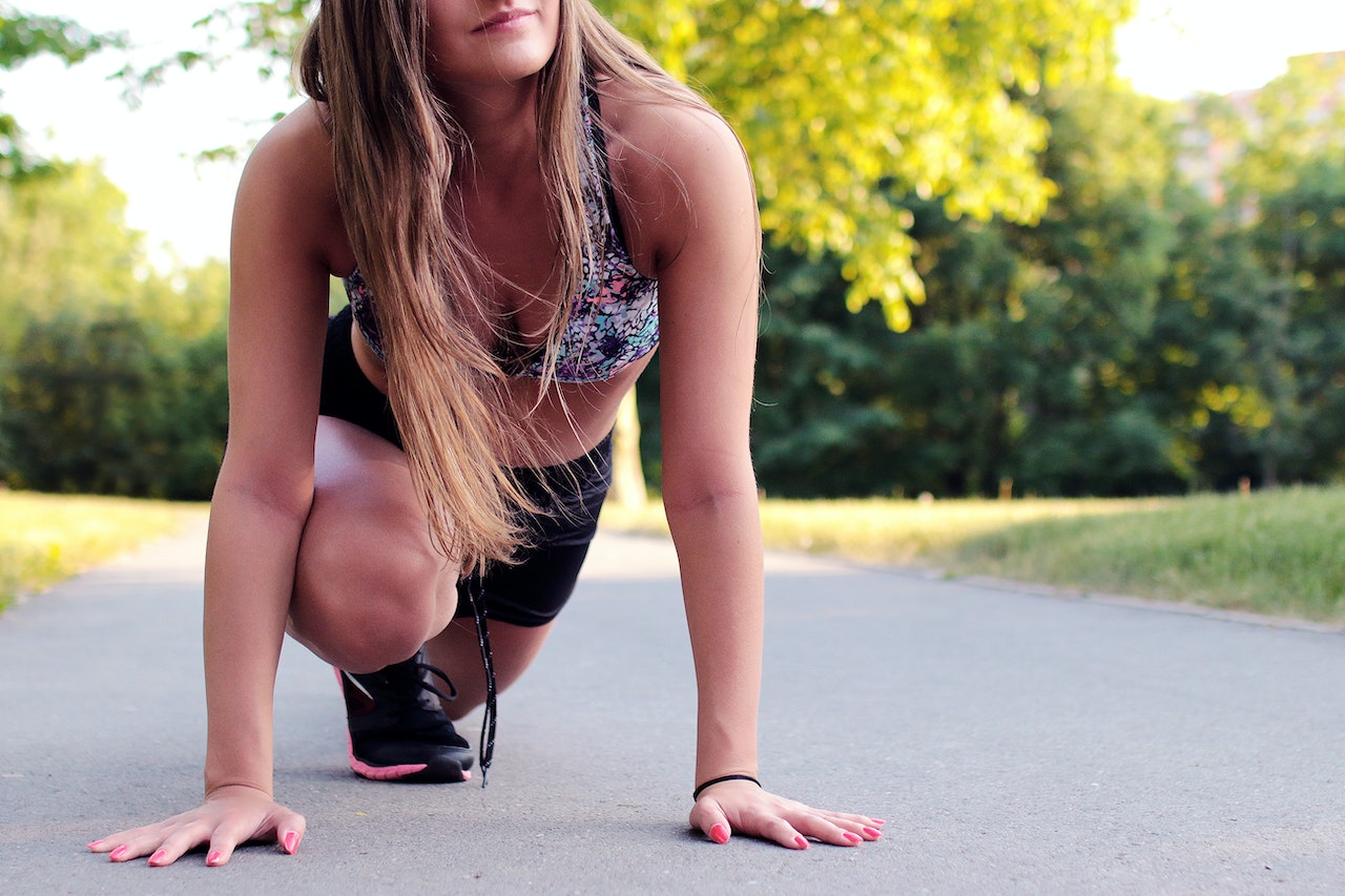 Woman in running gear squatting on ground